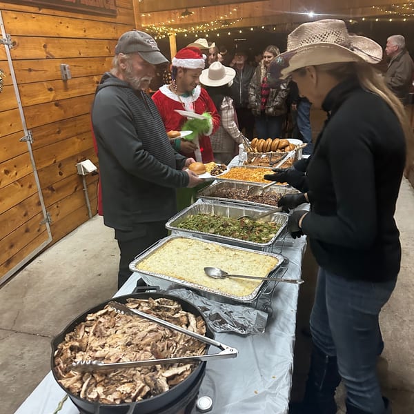 People in a rustic setting serving themselves Briskets BBQ from a buffet line.