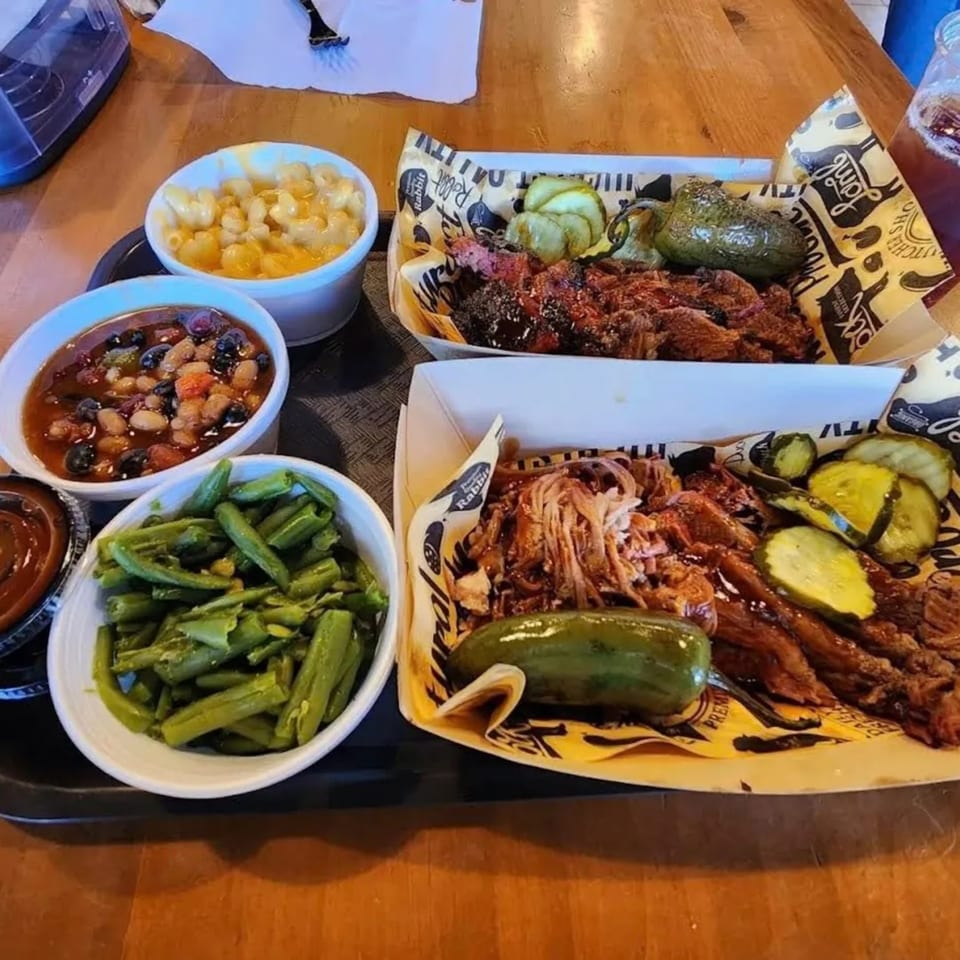 Two Briskets BBQ platters with pulled pork, brisket, pickles, jalapenos, mac and cheese, baked beans, and green beans.