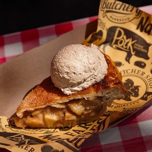 A slice of Briskets BBQ apple pie with a scoop of ice cream on branded paper.