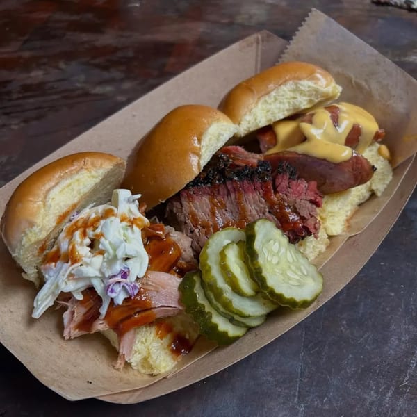 Brisket BBQ sliders with pulled pork, brisket, sausage, coleslaw, pickles, and cheese sauce.