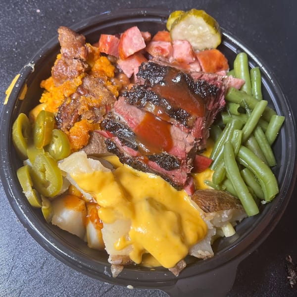 Brisket BBQ bowl with sliced brisket, sausage, green beans, baked beans, potatoes, cheese sauce, and jalapeños.
