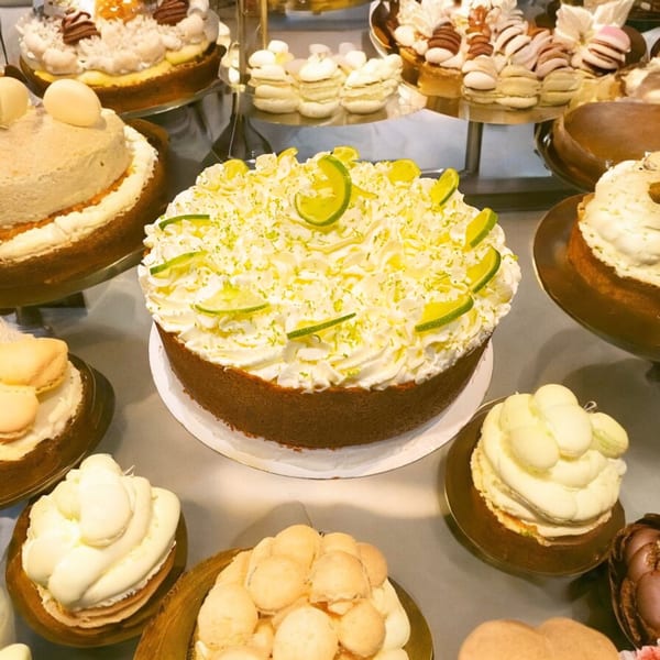A dessert display featuring a large key lime pie, other cakes, and small pastries.