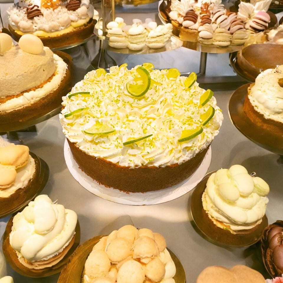 A dessert display featuring a large key lime pie, other cakes, and small pastries.