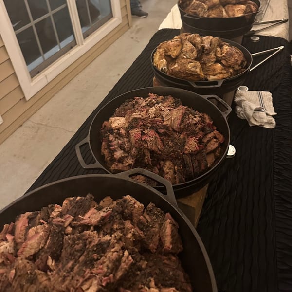 Four large cast iron pots filled with cooked meat, two with chicken and two with sliced beef.