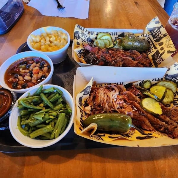 Two trays of Briskets BBQ with pulled pork, brisket, pickles, green beans, baked beans, and mac and cheese.